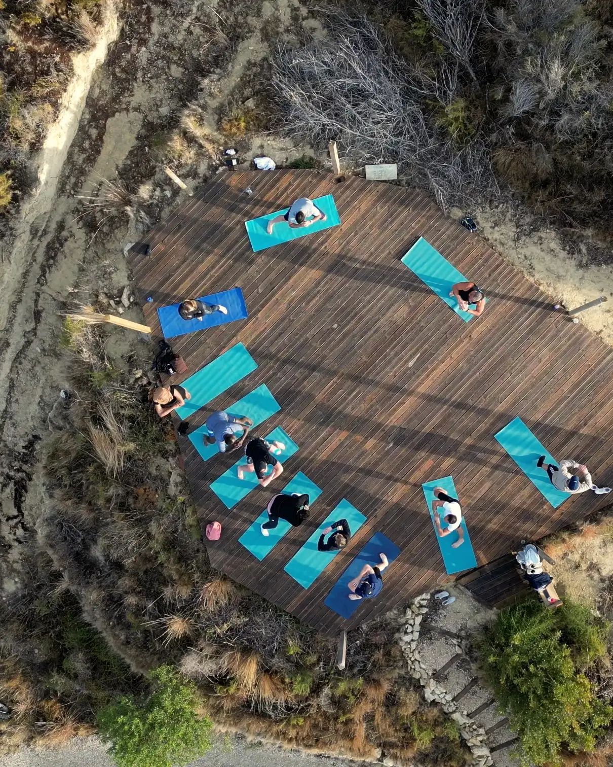 Seen from above: the group on their mats on a wooden deck in the hills