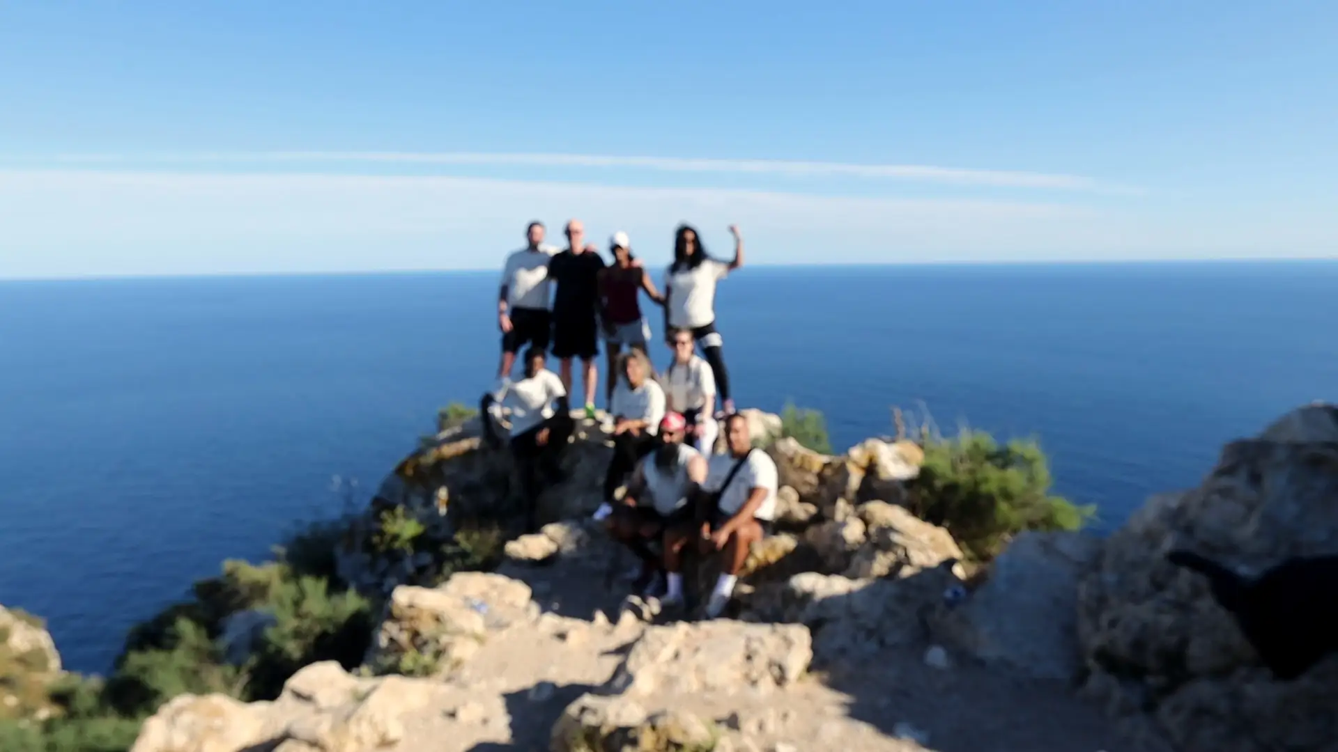 The group together on a rocky summit, open sea behind