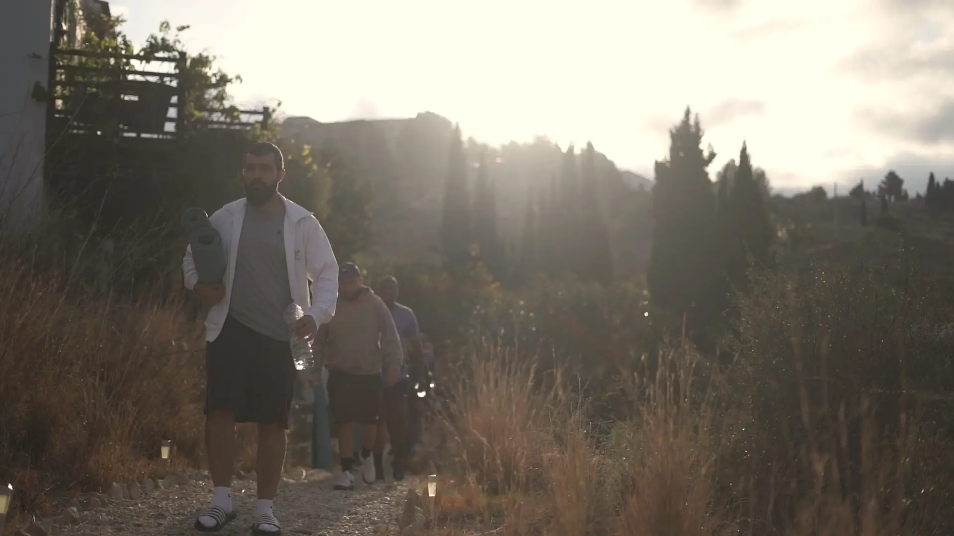 The group walking out at sunrise with mats under their arms, the sun behind them